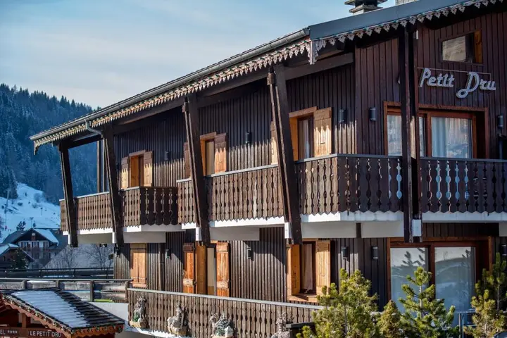 Hotel Le Petit Dru in Morzine, its timber chalet facade and balconies under snow