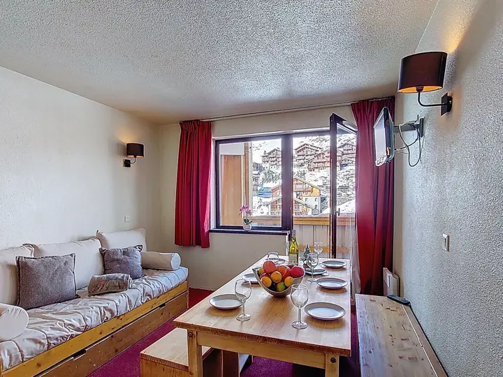 Living and dining area of the two-bedroom apartment at Les Olympiades, with a window looking over Val Thorens