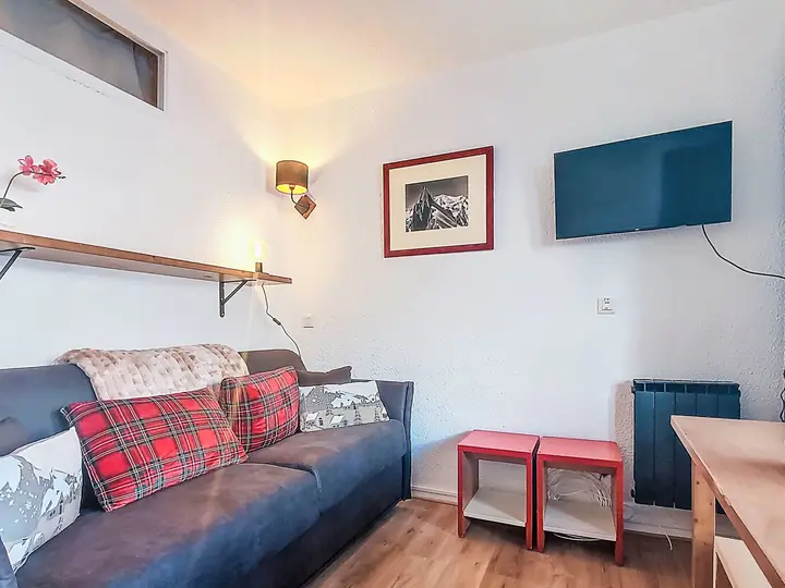 Living room of the two-room apartment at Les Olympiades, with a sofa, dining table and wall-mounted TV